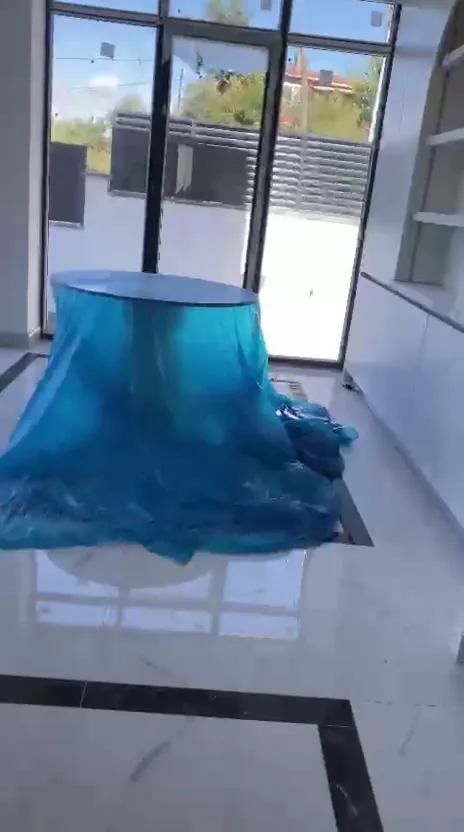 İnşaat sonrası villa salonu: yemek masası mavi koruma naylonuyla örtülü, mermer zeminde toz